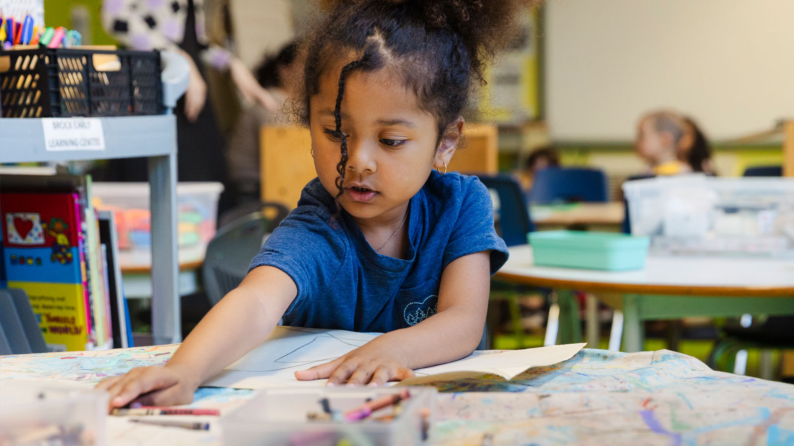 kindergarten student colouring at a desk in the after school program
